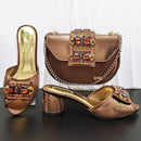 Gold high-heeled shoes and matching handbag with gemstone embellishments on a dark surface, Obroi