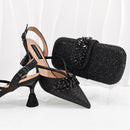 Black high-heeled shoes with decorative elements and a matching black clutch on a white background, Obroi