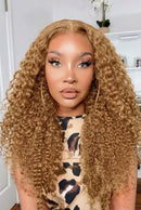 A side-by-side comparison of a woman wearing a long, curly wig. The wig has a warm golden-brown color with lighter blonde highlights, Obroi