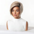 A woman wearing a short, layered wig with a side-swept bang and subtle gray-blonde highlights, styled on a mannequin bust against a clean white studio background, Obroi
