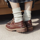 Brown loafers worn with white ribbed socks on a neutral background, Obroi