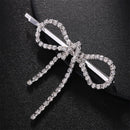 Silver bow-shaped hairpin with rhinestones on a black background, Obroi