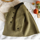 Green coat with black buttons on a white surface with decorative elements, Obroi