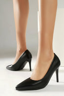 Black high-heeled shoes worn by a person on a neutral background, Obroi