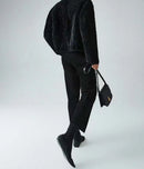 Person wearing a black outfit with a black handbag on a white background, Obroi