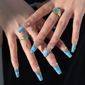 Obroi Close-up of hands with blue nail designs and decorative rings on a black background