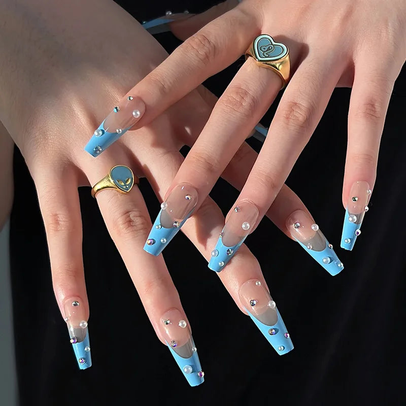 Obroi Close-up of hands with blue nail designs and decorative rings on a black background