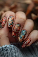 Close-up of a hand with intricately designed floral nail art in autumn colors, Obroi
