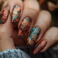 Close-up of a hand with intricately designed floral nail art in autumn colors, Obroi
