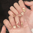 Hand with gold and clear nail design on a dark background, Obroi