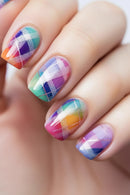 Colorful plaid nail design on a hand with a blurred background, Obroi