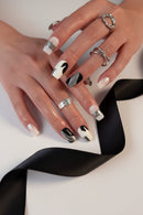 Close-up of hands with stylish nail design and multiple rings on a neutral background, Obroi