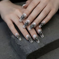 Close-up of hands with decorative nail art on a dark surface, Obroi
