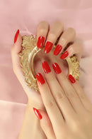 Hands with red nail polish holding a gold decorative mirror against a pink background, Obroi