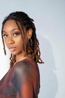 Braided synthetic dreadlock extensions shown on a model and as individual bundles, with a color gradient from black to brown and some gold and pink ombre options, branded with Obroi.