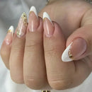 Close-up of a hand with white and gold nail polish on a neutral background, Obroi