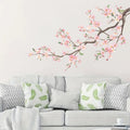 Gray sofa with decorative pillows and a cherry blossom branch wall decal on a light gray wall, Obroi