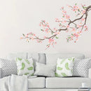 Gray sofa with decorative pillows and a cherry blossom branch wall decal on a light gray wall, Obroi