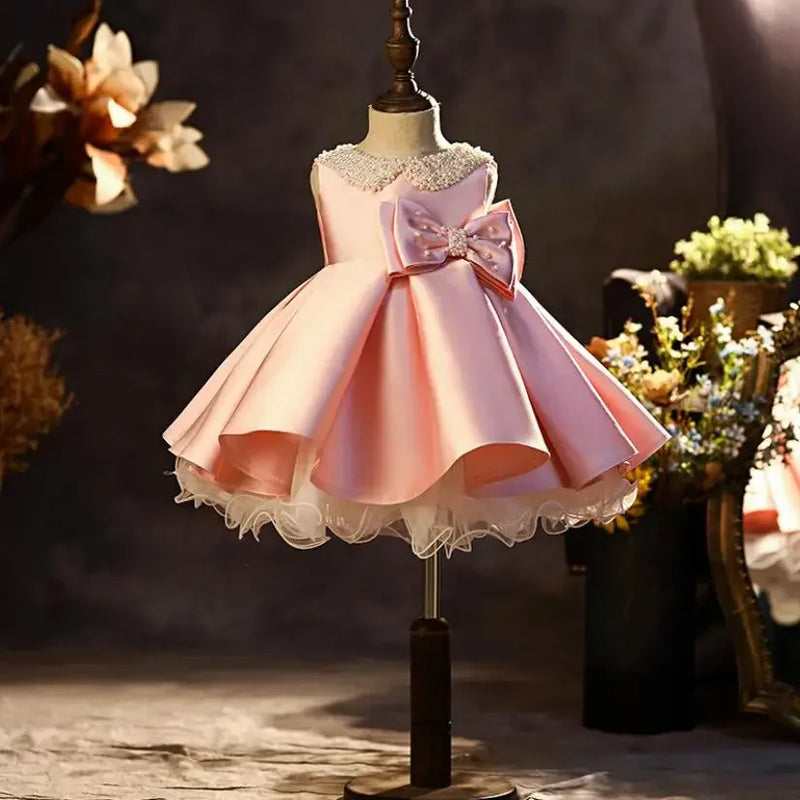 Pink dress with a large bow on a mannequin against a dark background