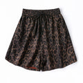 A pair of women's shorts featuring a brown and black leopard print pattern, an elastic waistband, and a black drawstring, shown flat on a white background, Obroi