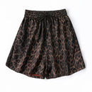 A pair of women's shorts featuring a brown and black leopard print pattern, an elastic waistband, and a black drawstring, shown flat on a white background, Obroi