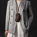 Person wearing a gray coat with a brown bag, on a black background, Obroi