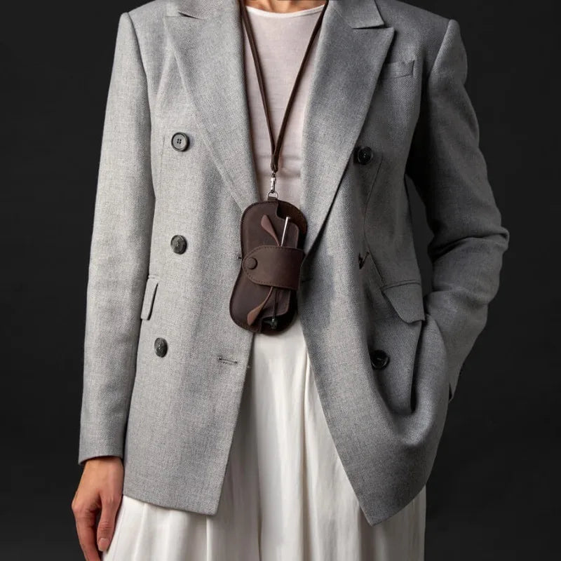 Person wearing a gray coat with a brown bag, on a black background, Obroi