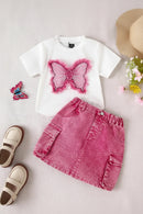 White t-shirt with pink butterfly design, pink denim skirt, sandals, and flowers on a light background, Obroi