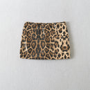 A leopard print sequin mini skirt with black and brown spots on a beige background, laid flat against a light gray textured wall, Obroi