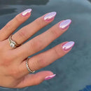 Hand with pink metallic nail polish and rings against a blurred water background, Obroi