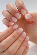 Close-up of a hand with pink and white gradient nail polish on a light background, Obroi