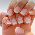 Close-up of a hand with pink and white gradient nail polish on a light background, Obroi