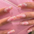 Obroi Close-up of hands with pink and white nail polish on a pink textured background