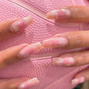 Obroi Close-up of hands with pink and white nail polish on a pink textured background