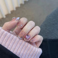 Close-up of a hand with decorative nails wearing a pink sweater, Obroi