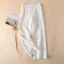 White linen pants on a beige background with a magazine and dried flower, Obroi