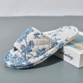 Floral-patterned slipper on a gray surface with a book in the background, Obroi