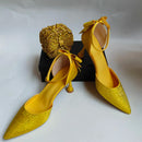 Yellow high-heeled shoes with decorative elements on a white background, Obroi