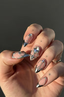Close-up of a hand with decorative nail art on a dark background, Obroi