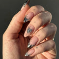Close-up of a hand with decorative nail art on a dark background, Obroi