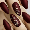 Nails with dark brown polish and white leaf designs on a neutral background, Obroi