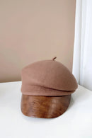 Brown beret with a textured brown base on a white surface, Obroi
