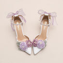 White high-heeled shoes with floral decorations and ribbons on a beige background, Obroi