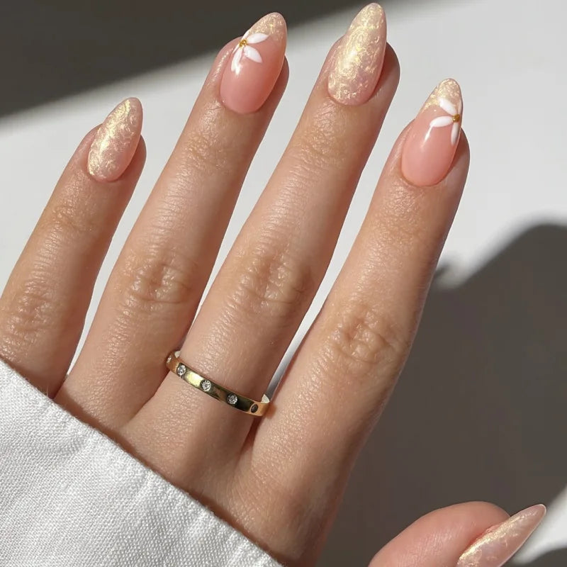 Obroi Hand with gold nail polish and a gold ring on a neutral background