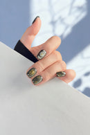 Hand with decorative nails holding a magazine against a blurred background, Obroi