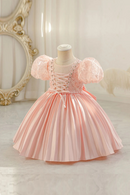 Pink dress on a mannequin against a decorative wall, Obroi