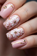 Nails with pink floral design and gold accents on a blurred background, Obroi