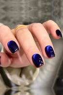 Hand with blue nail polish on a reflective surface, Obroi