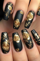 Black nails with gold floral designs on a hand, Obroi