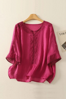 Pink blouse with lace details on a wooden hanger against a beige background, Obroi